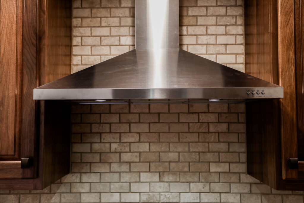 kitchen stove exhaust with beautiful wooden cabinets surrounding it