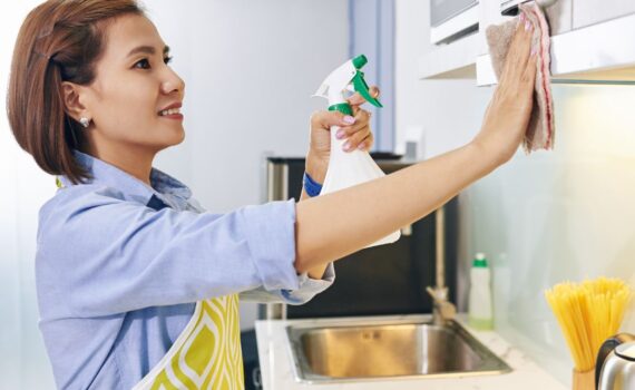 woman spray cleaning kitchen cabinets